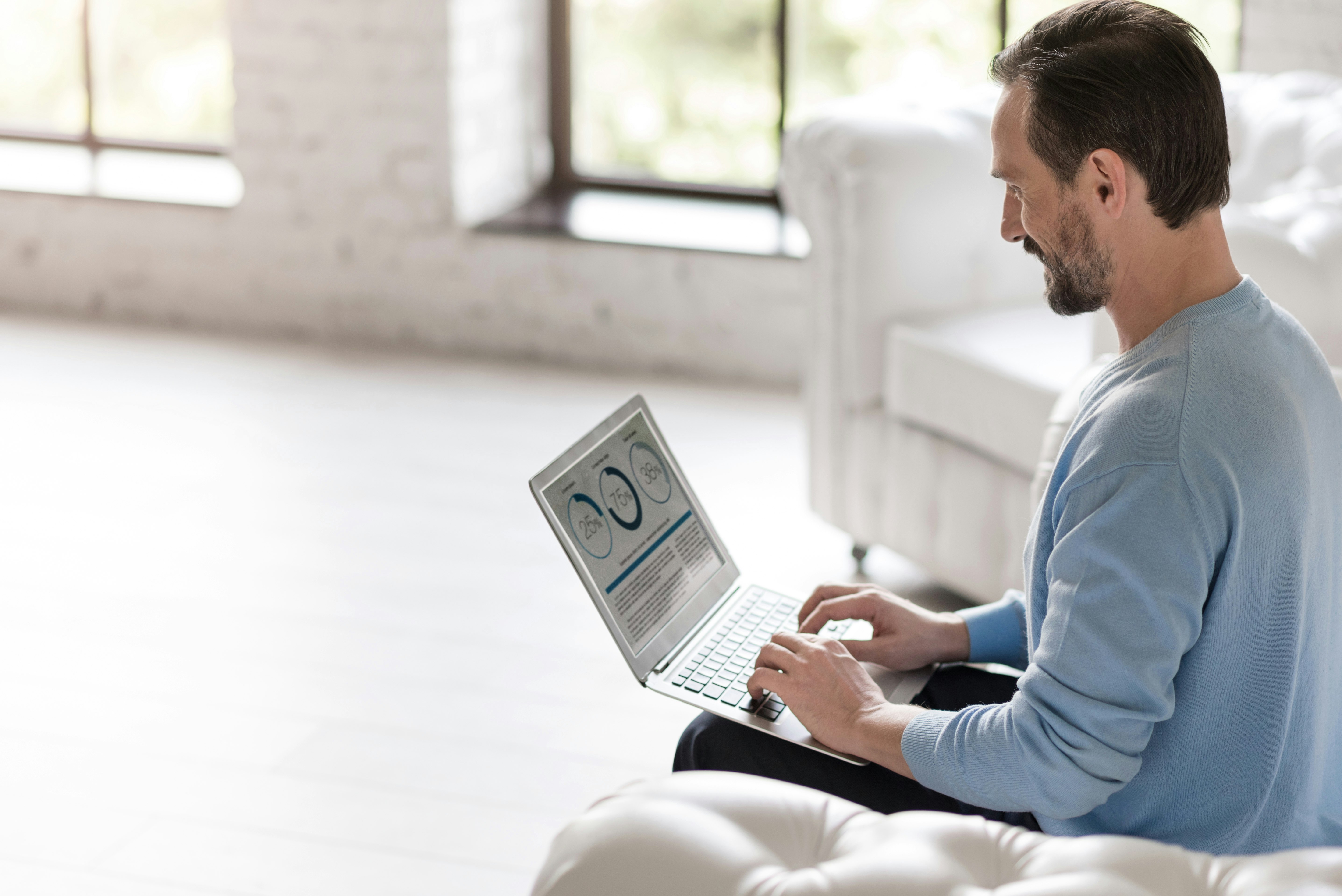 Statistical data. Hard working happy pleasant man looking at the screen and typing on a keyboard while working on a laptop